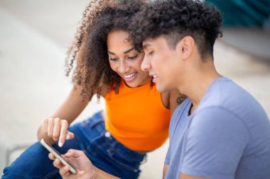 Birlikte cep telefonuna bakan genç bir çiftin portresi.