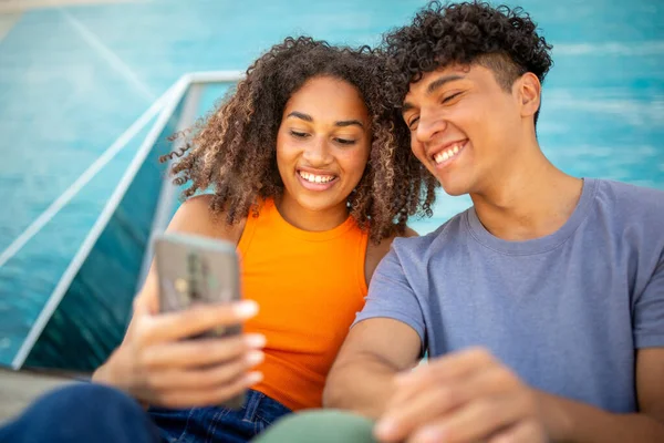 一緒に携帯を見ている若いカップルの笑顔の肖像 — ストック写真