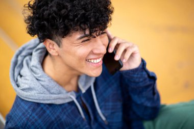 Yakın plan yakışıklı genç adam cep telefonuyla konuşuyor.