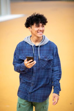 Gülümseyen portre, kıvırcık saçlı, cep telefonu tutan yakışıklı genç adam.