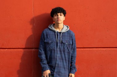 Portre, kırmızı duvarda duran havalı genç adam.