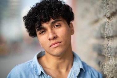 Kameraya bakan kıvırcık saçlı, havalı bir genç adam.