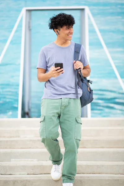 携帯電話とバッグで歩いているポートレートハンサムな若い男 — ストック写真
