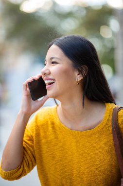 Cep telefonuyla konuşurken gülümseyen genç bir kadın portresi