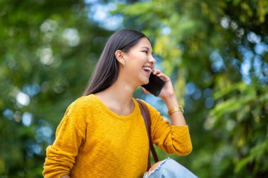 Cep telefonuyla konuşan mutlu genç bir kadın portresi.