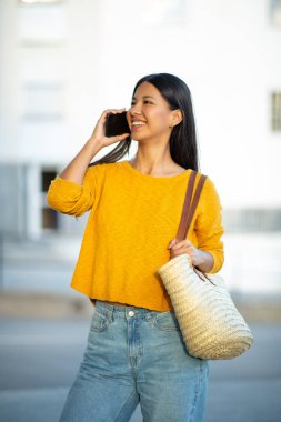 Dışarda cep telefonuyla konuşan gülümseyen güzel bir kadın. 