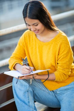 Kitapta oturan ve yazan genç bir kadın portresi.