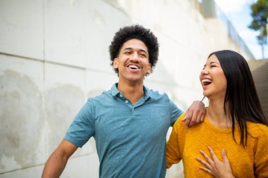 Birlikte yürüyen ve gülen mutlu genç Latin çift portresi.