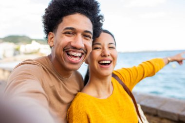 Deniz kenarında selfie çeken neşeli genç bir çift.