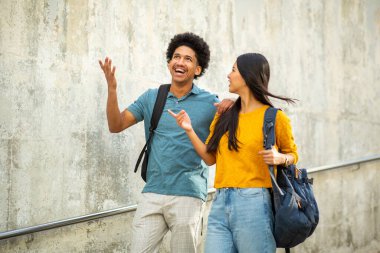 Çantalarla yürüyen iki mutlu öğrenci portresi.