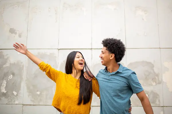 Potret Pasangan Muda Tersenyum Berdiri Oleh Dinding Dengan Tangan Terangkat — Stok Foto