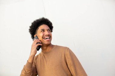 Portre gülümseyen Afrikalı Amerikalı genç adam cep telefonuyla konuşuyor.