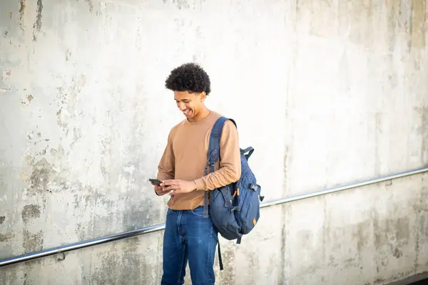 携帯電話を見ているバッグを持つ肖像画の若者 — ストック写真