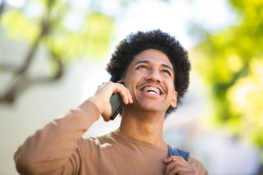 Neşeli İspanyol öğrenci açık havada mutlu bir Ypung adamının telefon konuşması yaparken çekilmiş yakın plan portresini seviyor..
