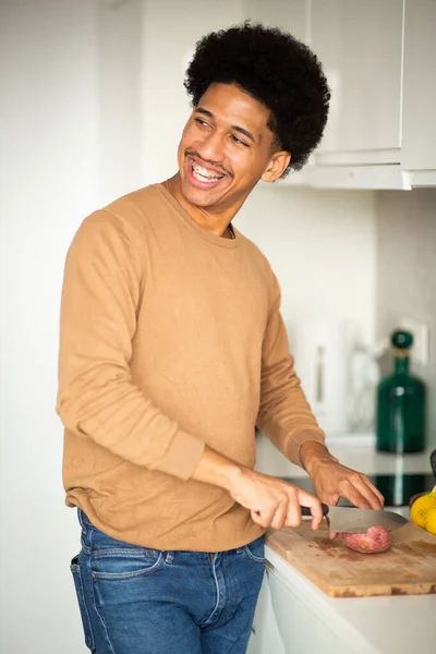 Portrait of young man cutting food in kitchen