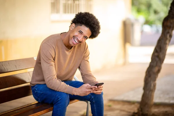 Potret Pria Muda Tersenyum Duduk Dengan Ponsel Tangan — Stok Foto