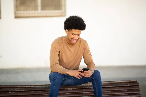 Pria Muda Yang Bahagia Duduk Luar Ruangan Bangku Memegang Ponsel — Stok Foto
