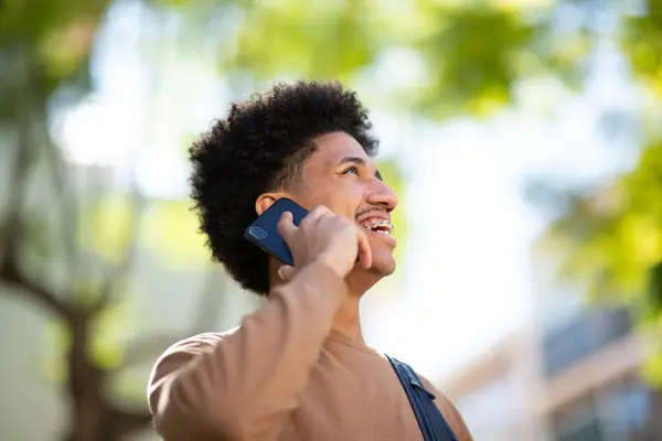 一个年轻的非裔美国人在用手机聊天的时候笑得紧紧的 免版税图库图片