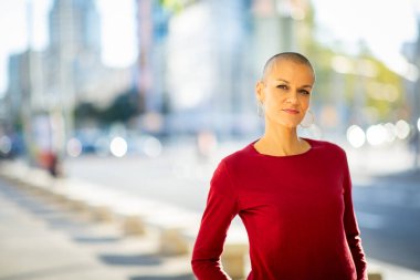 Şehirde dikilen kafası tıraşlı bir kadının portresi.