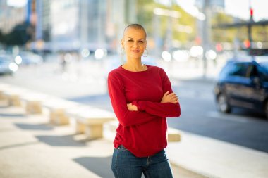 Şehirde kafası tıraşlı, kendine güvenen bir kadının portresi.