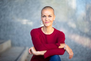 Kafası tıraşlı, orta yaşlı güzel bir kadının portresi.