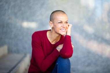 Kafası tıraşlı, gülümseyen güzel bir kadının portresi.