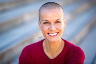 Saçları tıraşlı, gülümseyen kadın portresi.