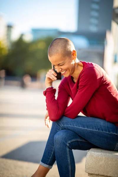 Portrait of shaved head woman talking with cellphone