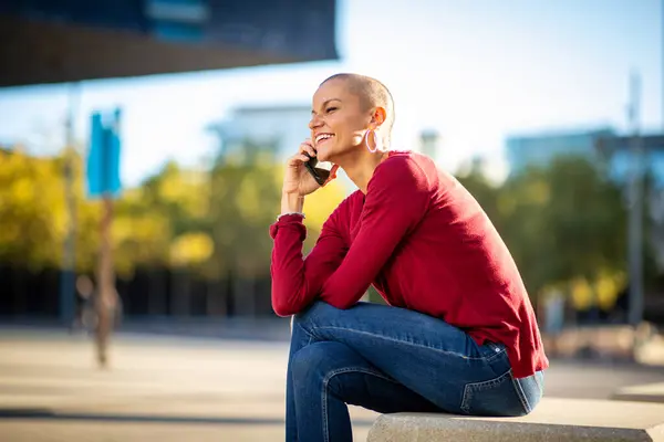 Portrait of shaved head woman talking with phone in the city