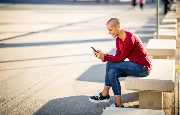 携帯電話を持って街の屋外に座っている女性の肖像画 — ストック写真