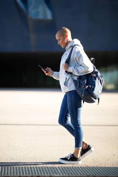 城市里拿着手机走路的城市妇女的全身侧像 免版税图库图片