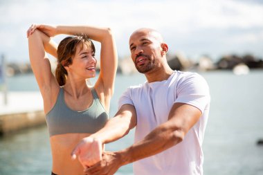 dinamik ikili aktif bir yaşam tarzının keyfini çıkarırken liman kenarında esniyorlar ve fitness yapıyorlar.