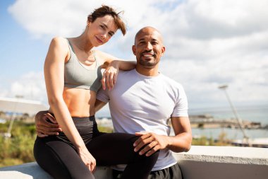 Erkek ve kadın, manzaralı bir arka planda rahat ve samimi bir anı paylaşıyor.