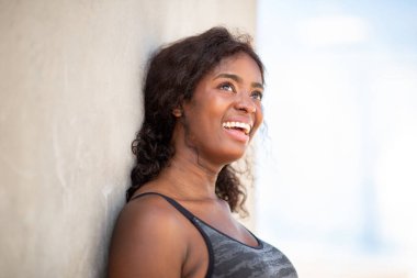 Afrikalı kadının portresi duvara yaslanmış, yüzü yukarıya doğru eğilmiş ve içten bir gülümsemeye dönüşmüş..