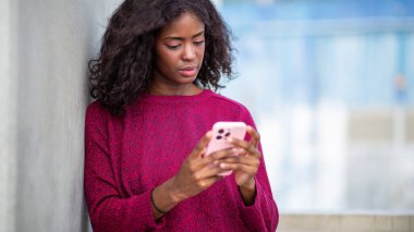 Genç Afrikalı kadın cep telefonundan mesajları kontrol ediyor.