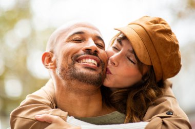 Mutlu bir çift, eşinin sırtına binip onu öperken aynı sevgi dolu anı paylaşır.