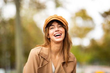 Dışarda şapkası ve ceketiyle gülen kadın portresi