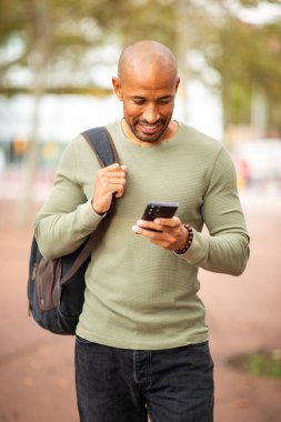 Portre stili bir adam şehir dışında geziyor, cep telefonuna bakıyor.
