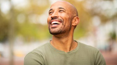 Kapalı portre sakallı, kel adam gülüyor ve dışarı bakıyor.