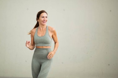 Sağlıklı bir kadın duvarın yanında koşuyor.