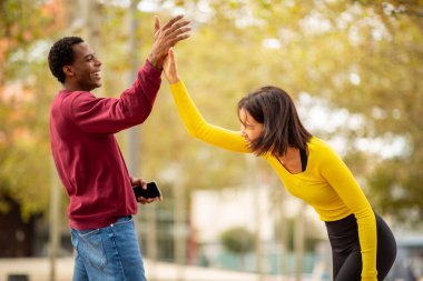 İki genç arkadaş bir beşlikle kutlama yapıyor ve dışarıda gülüyorlar..