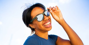 Güneş gözlüklü genç bayan gülüyor.