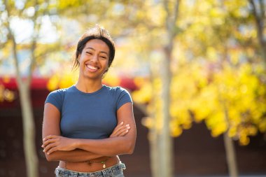 Dışarıda kolları bağlı gülümseyen kendine güvenen genç bir kadın.