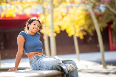 Gülümseyen genç İspanyol kadın dışarıda oturuyor.