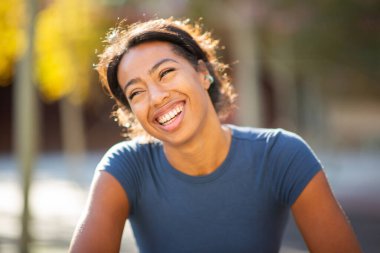 Gülen ve yüzünü çeviren neşeli genç bir kadının yakın plan portresi.