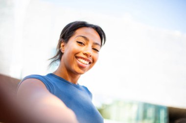 Açık havada gülümseyen genç bir kadının selfie portresi.