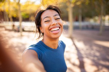 Dışarıda gülen neşeli genç bir kadının selfie 'si.