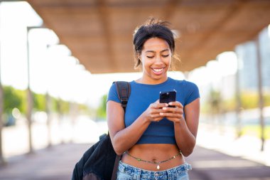 Şehirde cep telefonu kullanan çantalı genç İspanyol kadın.