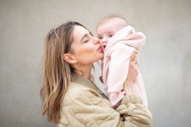 Portre anne nazikçe bebeğini yanağından öpüyor.