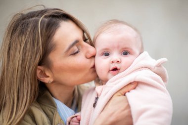 Genç annenin yakın portresi sevgiyle bebeğini öpüyor.
